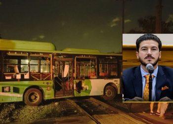 Nighttime scene of a green bus on railroad tracks with doors open, overlaid by a portrait of a man in a suit speaking at a microphone.